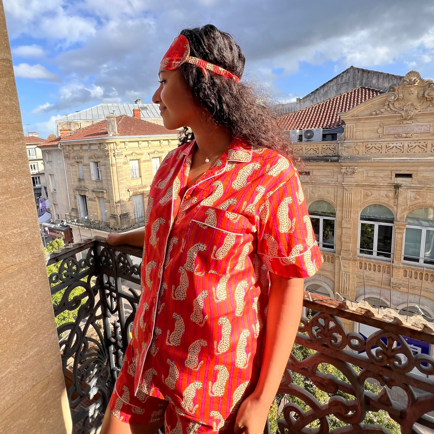 Jeune femme portant un pyjama court en coton indien, imprimé léopards sur rayures orange et fuchsia, chemise à manches courtes et short assorti