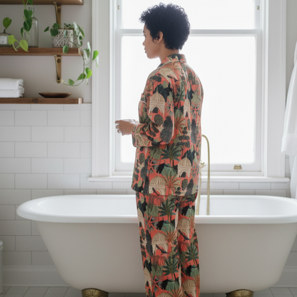 Femme portant un pyjama long femme en coton indien, imprimé exotique avec paons, et motifs végétaux sur fond corail, chemise manches longues et pantalon assorti