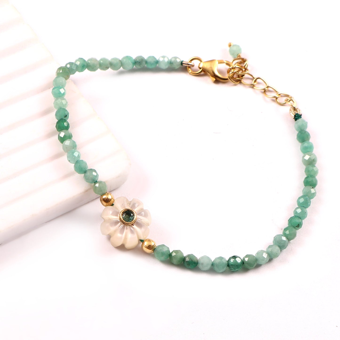 Bracelet Amara composé de perles d’émeraude avec fleur en nacre ornée d’une émeraude, vue de côté, création Mademoiselle Azalée
