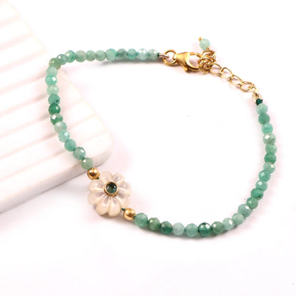 Bracelet Amara composé de perles d’émeraude avec fleur en nacre ornée d’une émeraude, vue de côté, création Mademoiselle Azalée