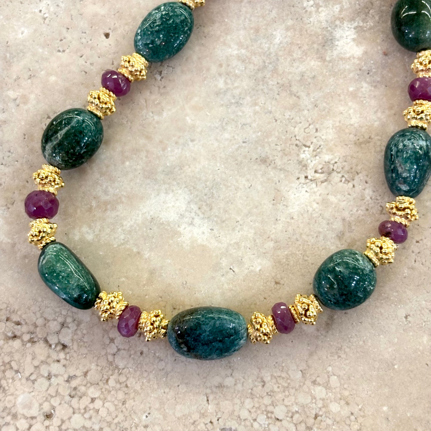 Détail du collier Azalée composé d’aventurines vert intense, de rubis facettés aux éclats profonds et d’intercalaires plaqués or.