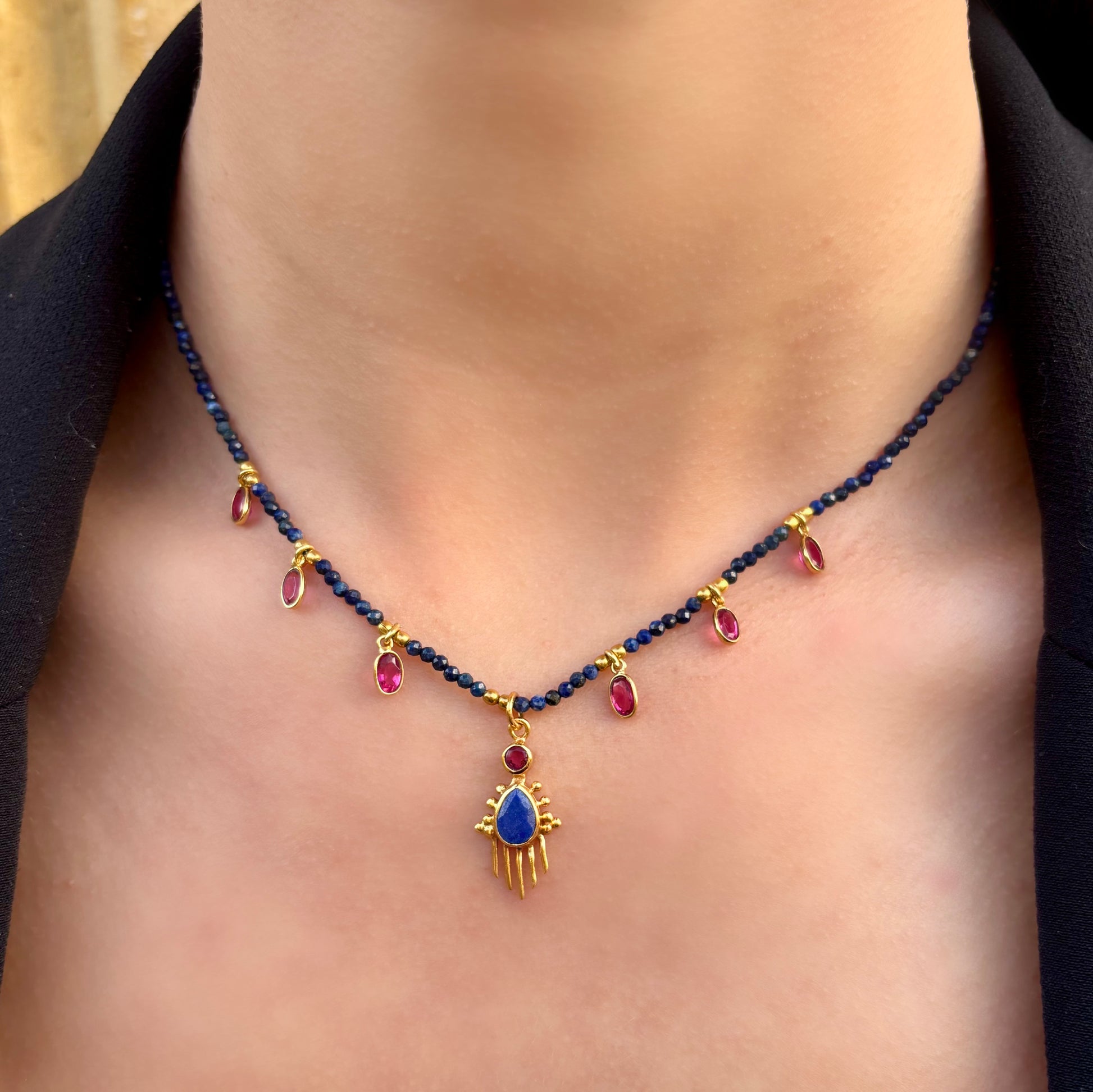 Collier Birdy Mademoiselle Azalée à Agen porté, composé de perles de lapis-lazuli, pendentifs gouttes framboise et médaille centrale dorée ornée d’une pierre bleue