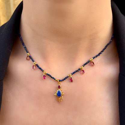 Collier Birdy Mademoiselle Azalée à Agen porté, composé de perles de lapis-lazuli, pendentifs gouttes framboise et médaille centrale dorée ornée d’une pierre bleue