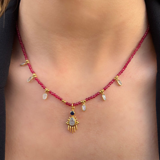 Collier Birdy Mademoiselle Azalée à Agen, porté, en perles rubis avec gouttes de pierre de lune et pendentif central doré serti d’une pierre nacrée