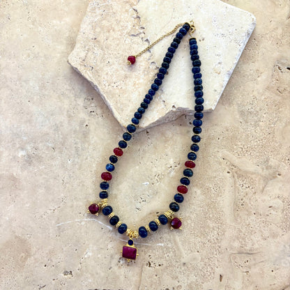 Collier Sophia composé de perles de sodalite bleu profond, de quartz framboise facetté et d’intercalaires plaqués or, présenté à plat sur une surface en pierre claire.