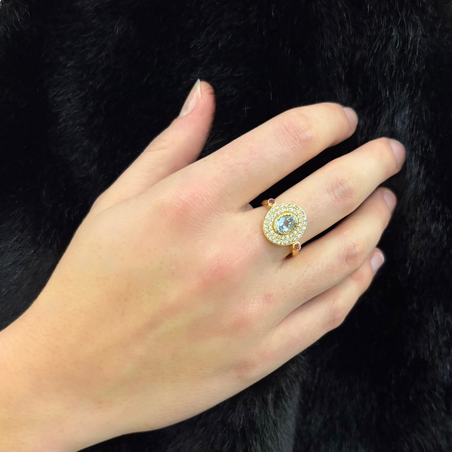 Bague Devi en argent 925 plaqué or portée à la main, avec topaze bleue centrale, quartz roses et oxydes de zirconium, création Mademoiselle Azalée à Agen