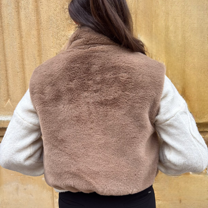 Gilet sans manches taupe en fausse fourrure, porté sur un pull torsadé écru, vue de dos