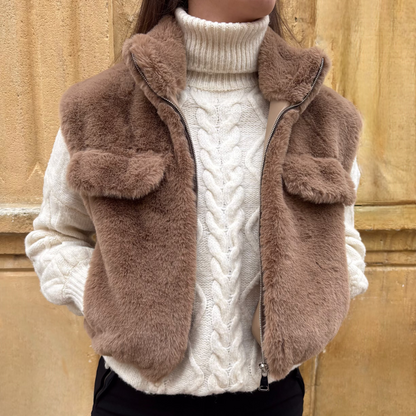 Gilet sans manches taupe en fausse fourrure, porté sur un pull torsadé écru, vue de face
