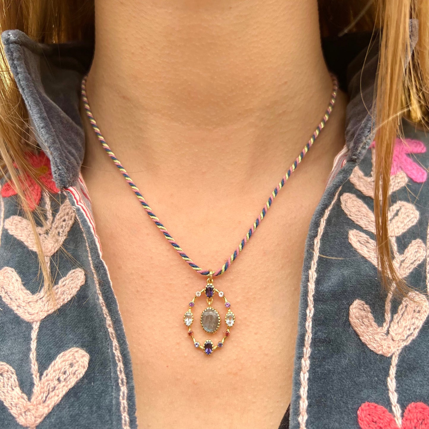 Collier Goa porté, avec pendentif en labradorite entouré de pierres fines multicolores montées sur apprêts plaqué or, suspendu à un cordon torsadé.