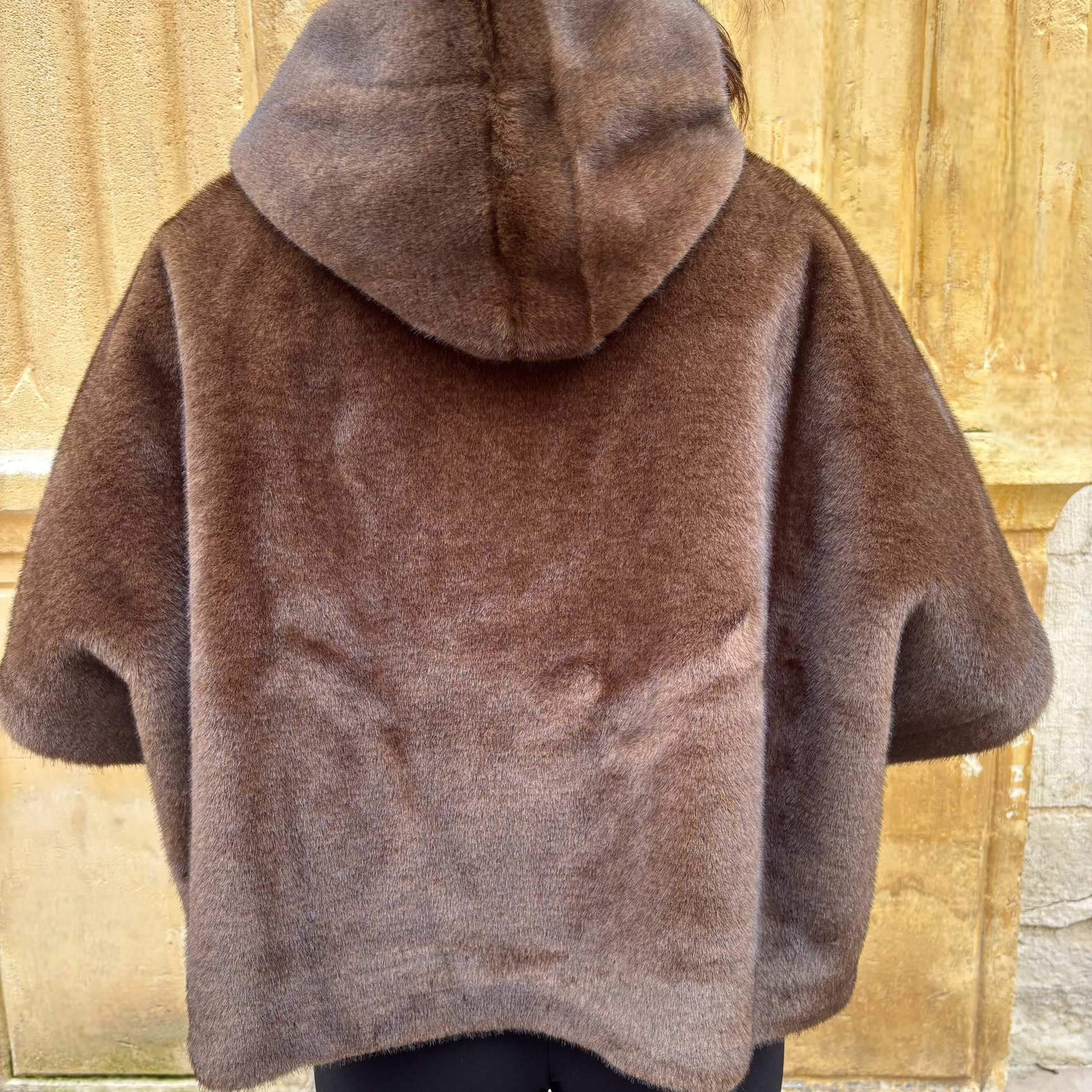 Cape marron en fausse fourrure portée de face, avec fermeture zippée et col montant.