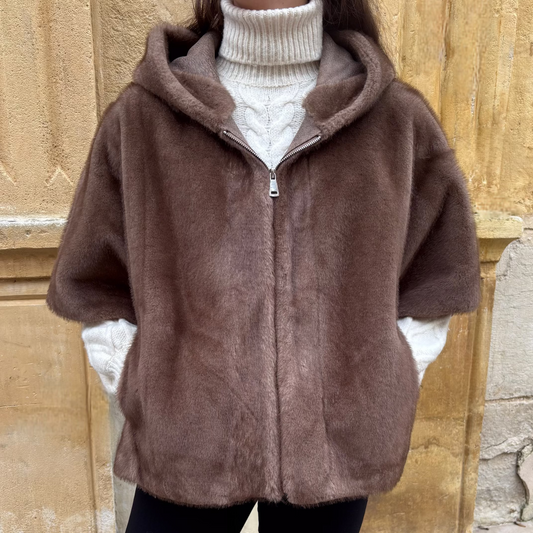 Cape taupe en fausse fourrure avec capuche, portée de face, fermeture zippée et manches courtes, superposée à un pull écru