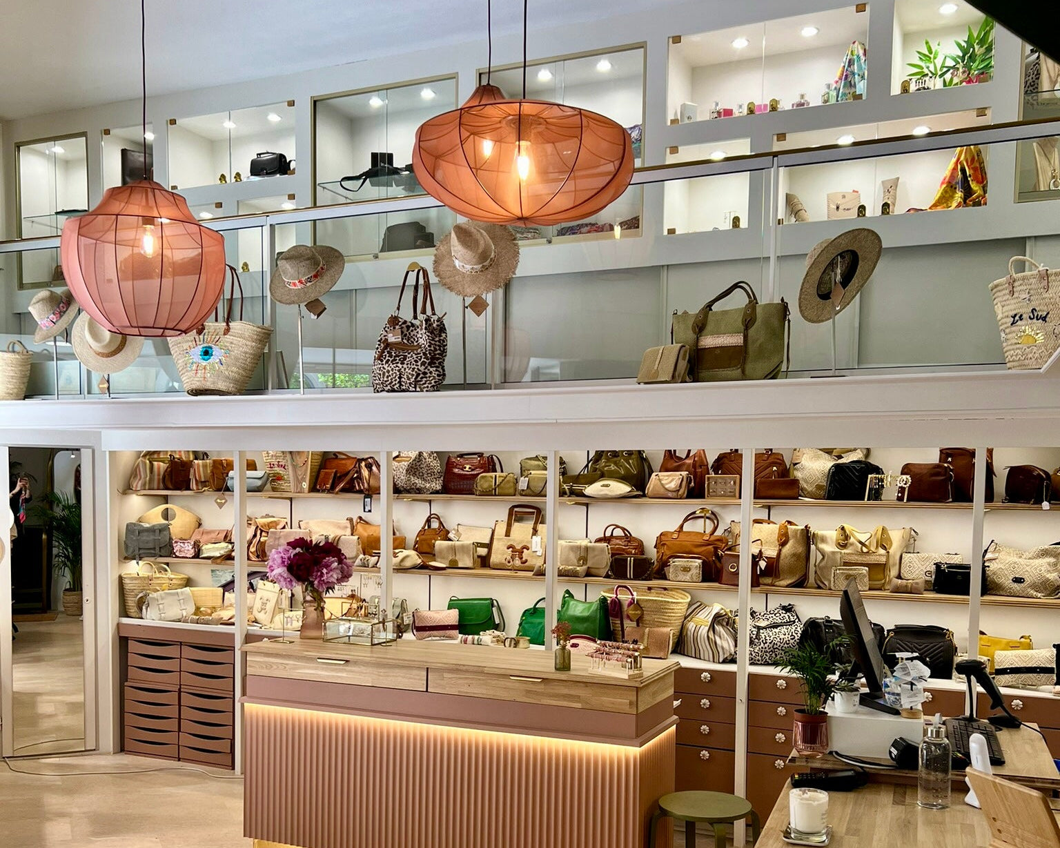 Intérieur de la boutique Mademoiselle Azalée à Agen, présentant un comptoir éclairé, des étagères de sacs et d’accessoires, dans une ambiance chaleureuse et raffinée.