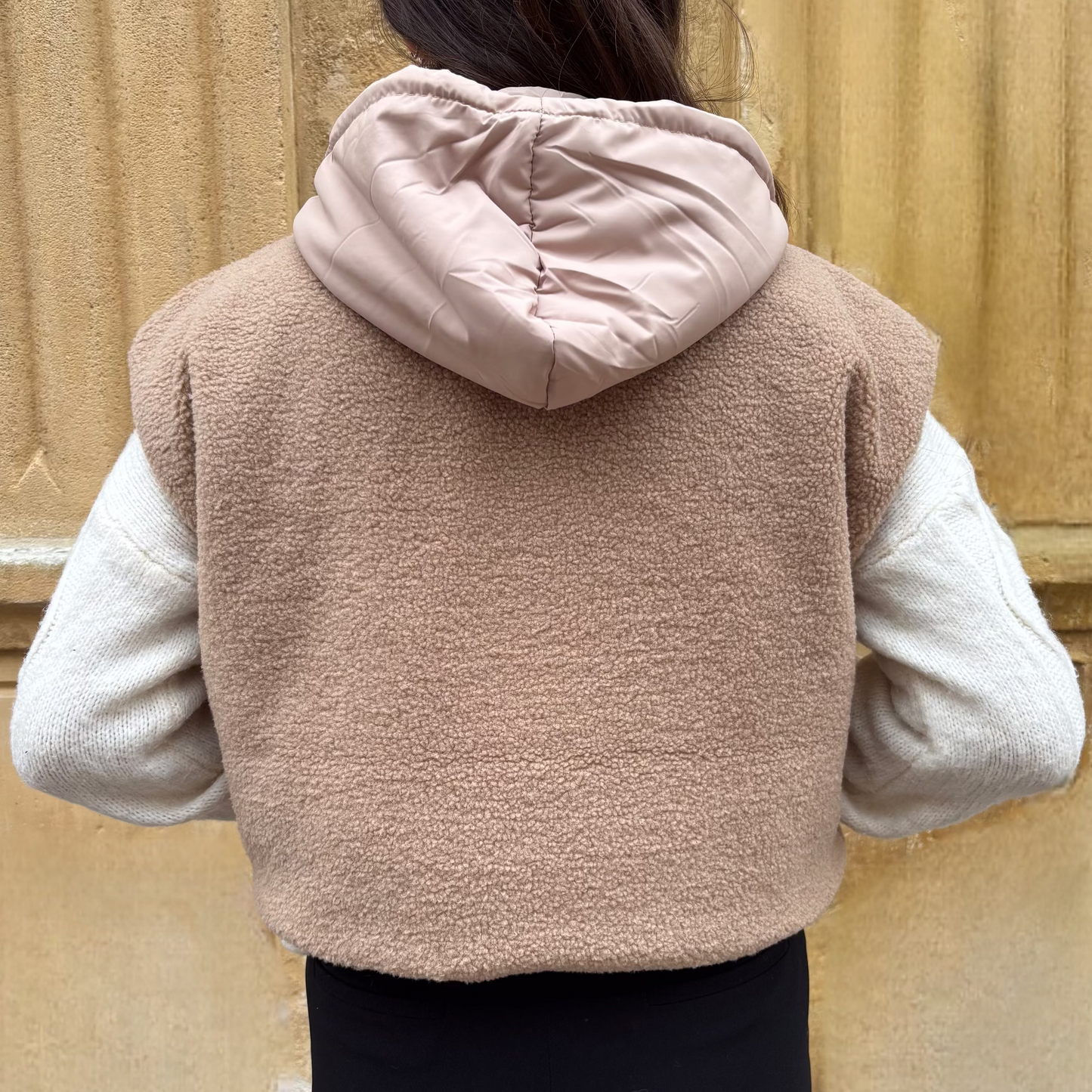 Gilet sans manches beige en fausse fourrure, porté sur un pull torsadé écru, vue de dos