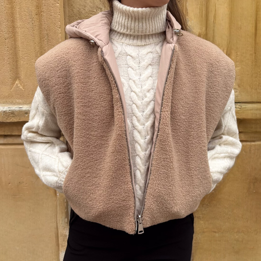 Gilet sans manches beige en fausse fourrure, porté sur un pull torsadé écru, vue de face