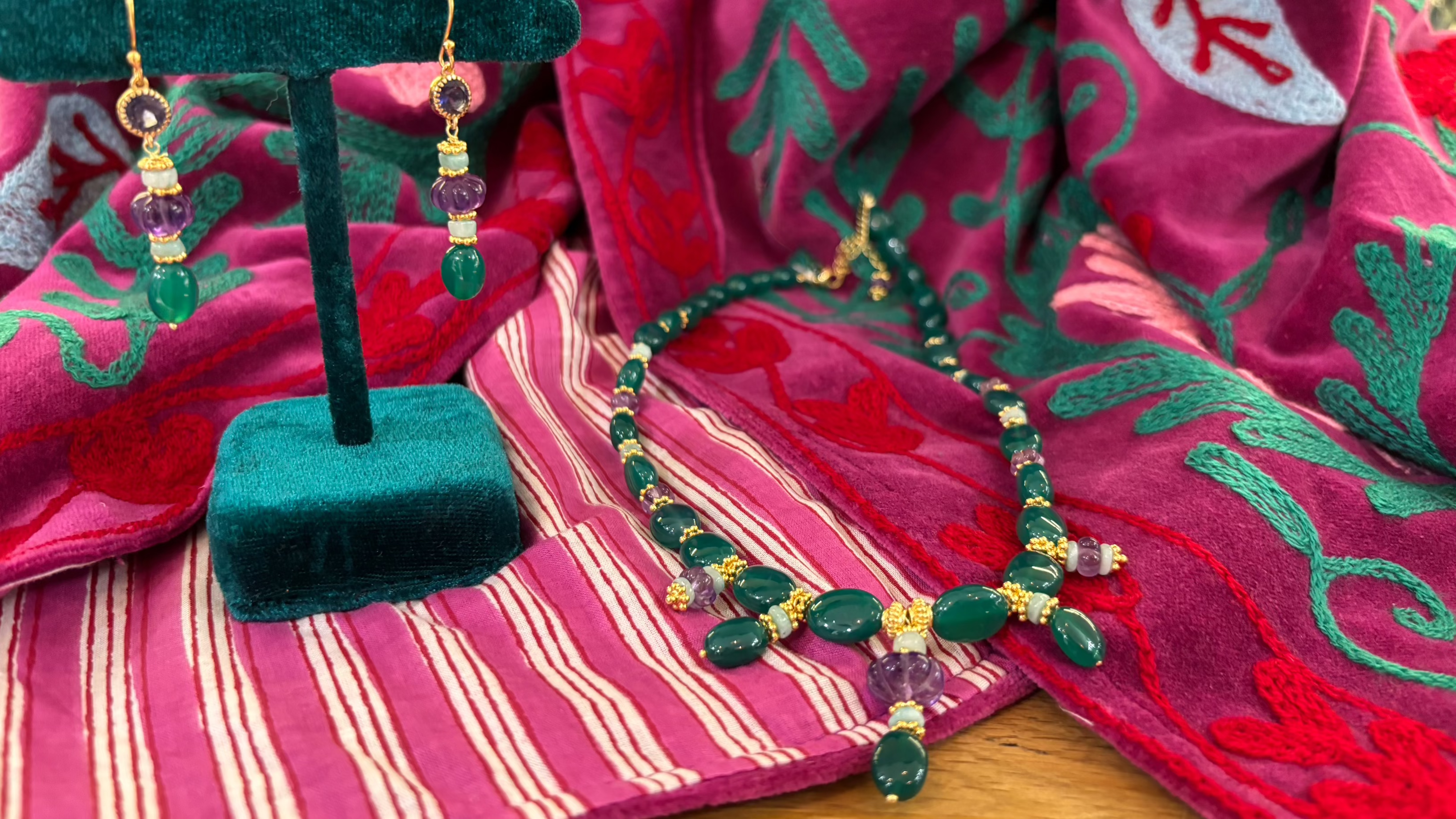 Collier artisanal en pierres naturelles, onyx vert et améthyste avec boucles d’oreilles assorties, création Mademoiselle Azalée à Agen, exposé sur une veste Suzani rose brodée